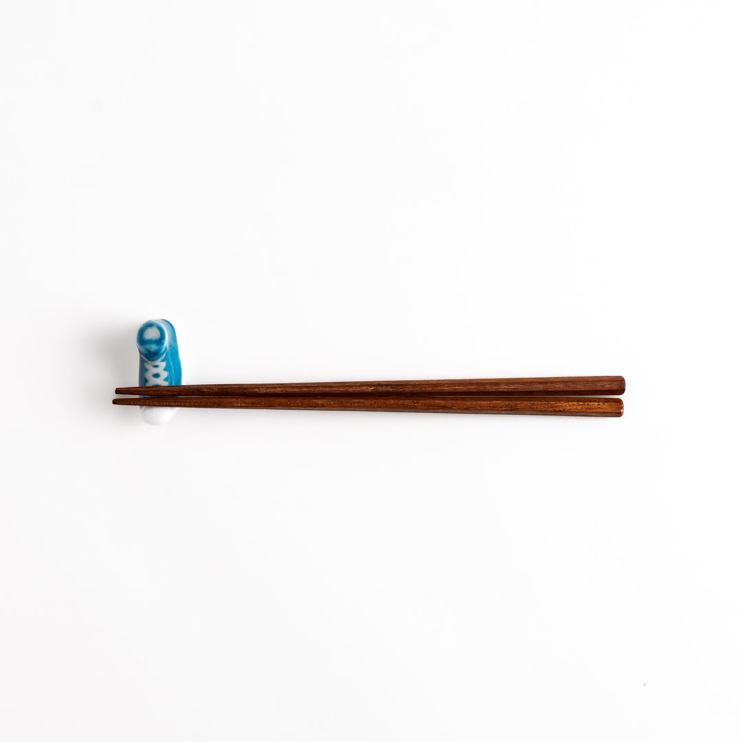 Light Blue Canvas Sneaker Chopstick Rest holding wooden chopsticks, showcasing its vibrant design and practical functionality.