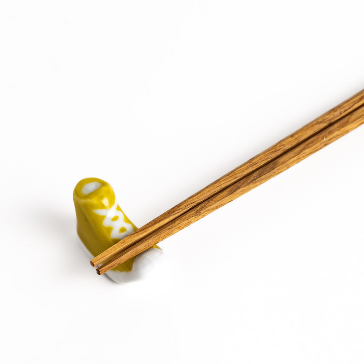 Yellow Canvas Sneaker Chopstick Rest holding wooden chopsticks, showcasing its vibrant design and practical functionality.