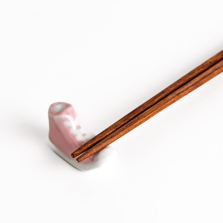 Pink Canvas Sneaker Chopstick Rest holding wooden chopsticks, showcasing its vibrant design and practical functionality.