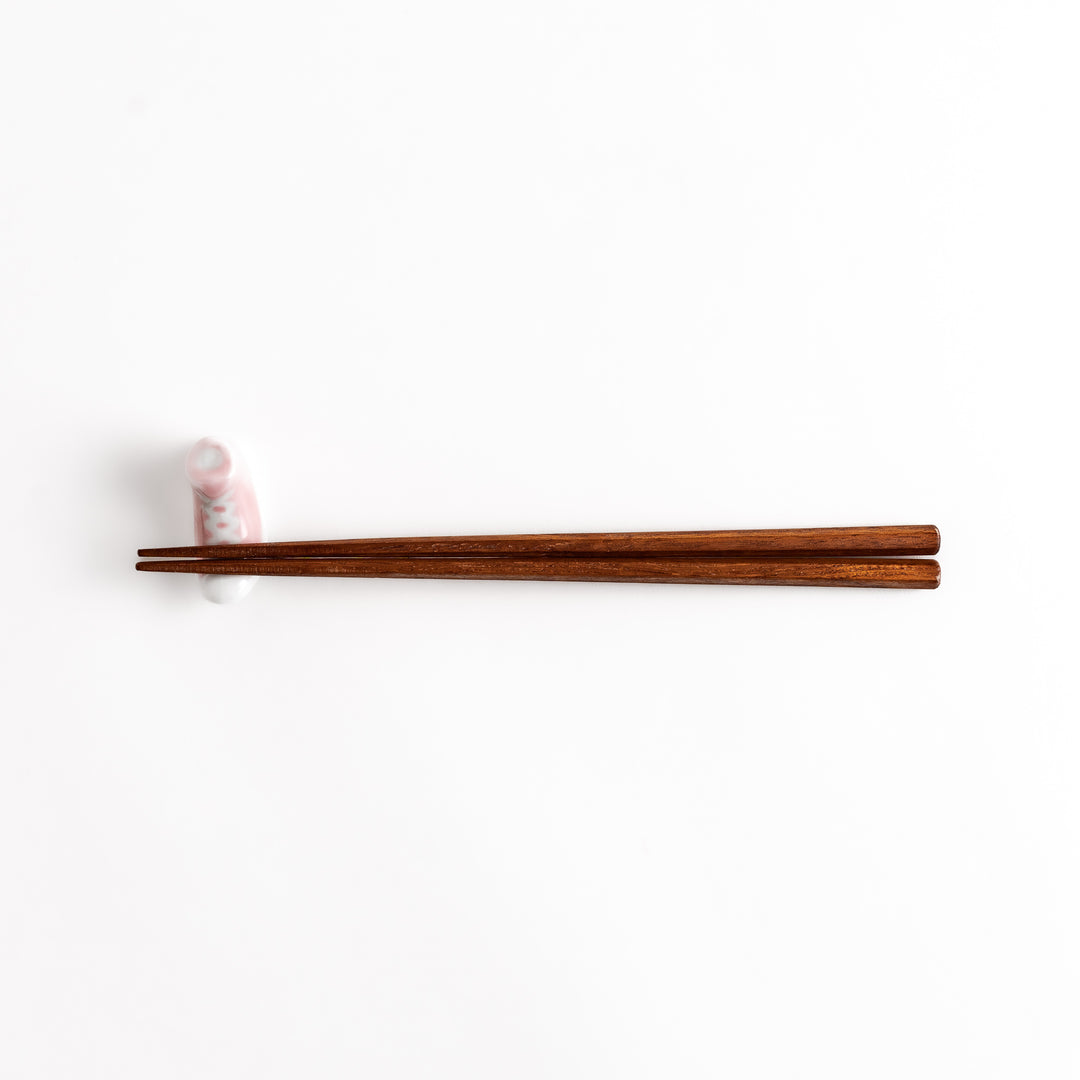 Pink Canvas Sneaker Chopstick Rest holding wooden chopsticks, showcasing its vibrant design and practical functionality.