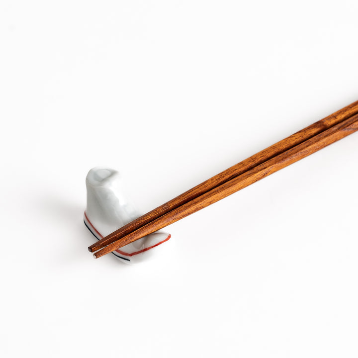 White Canvas Sneaker Chopstick Rest holding wooden chopsticks, showcasing its vibrant design and practical functionality.