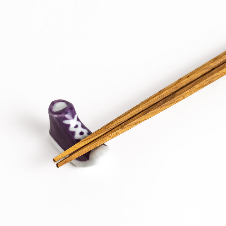 Purple Canvas Sneaker Chopstick Rest holding wooden chopsticks, showcasing its vibrant design and practical functionality.