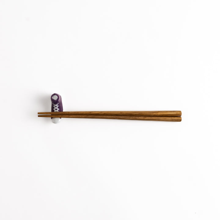 Purple Canvas Sneaker Chopstick Rest holding wooden chopsticks, showcasing its vibrant design and practical functionality.