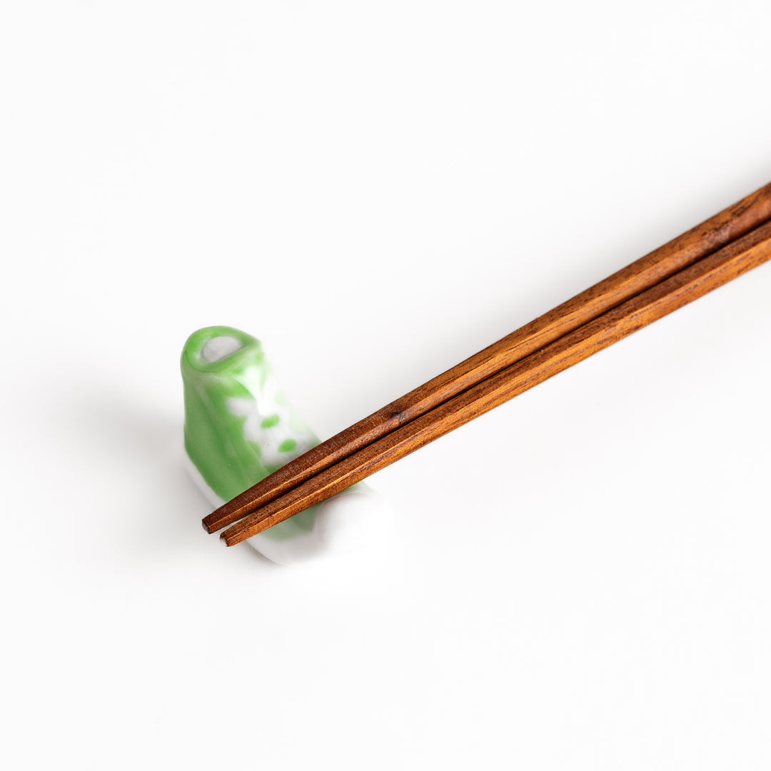 Light Green Canvas Sneaker Chopstick Rest holding wooden chopsticks, showcasing its vibrant design and practical functionality.