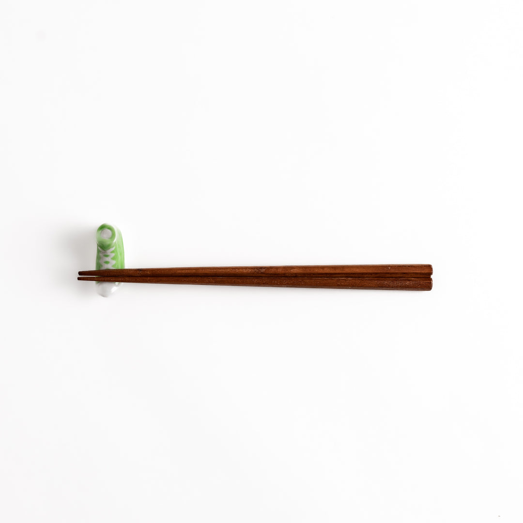 Light Green Canvas Sneaker Chopstick Rest holding wooden chopsticks, showcasing its vibrant design and practical functionality.