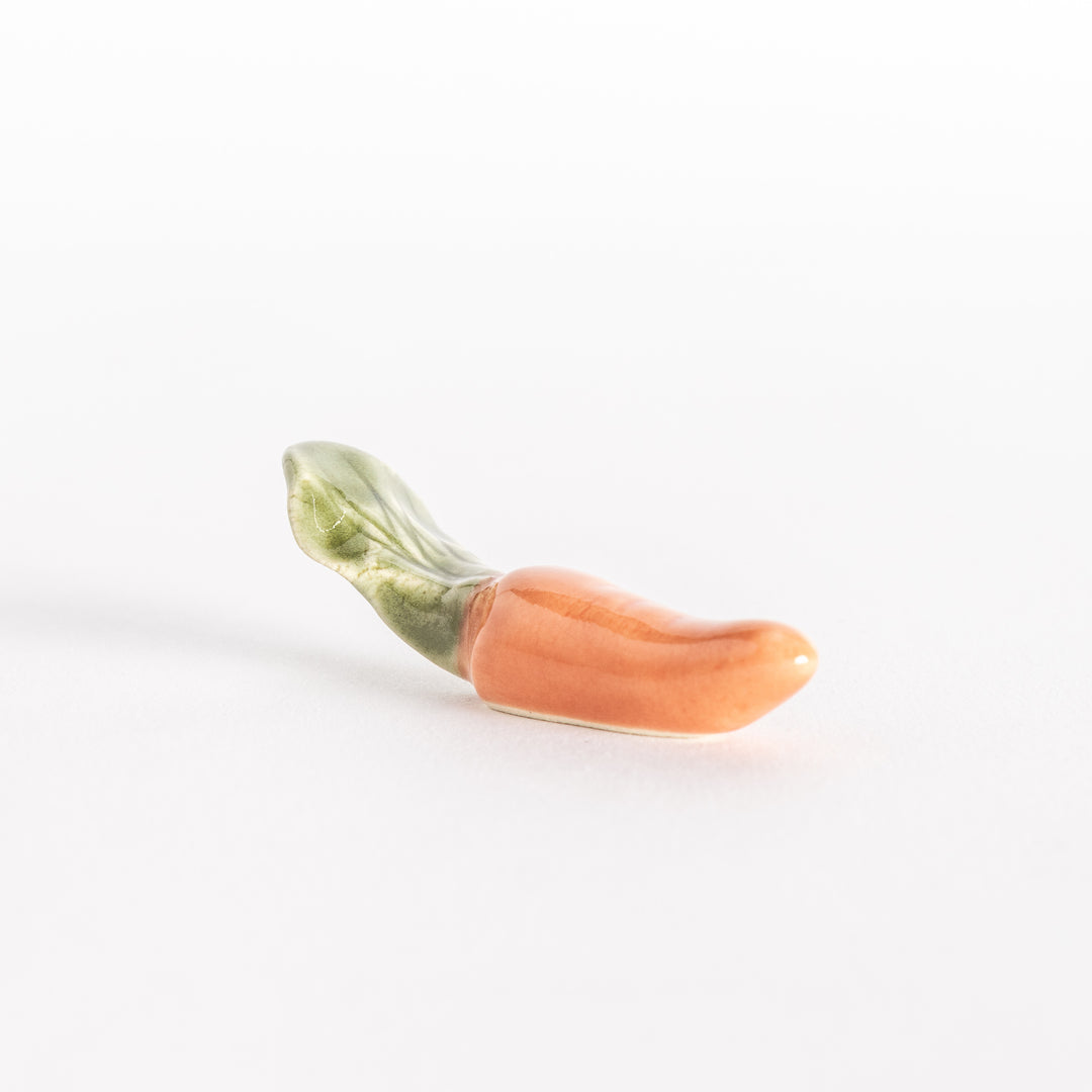 Side profile of the carrot-shaped ceramic chopsticks rest, highlighting its smooth surface and playful design.