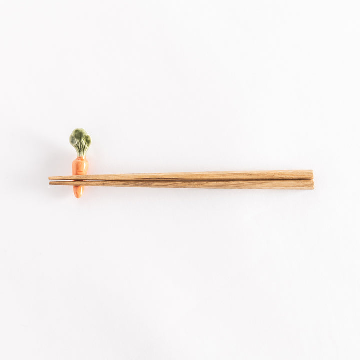 Orange carrot-shaped chopsticks rest holding chopsticks, showcasing playful design.