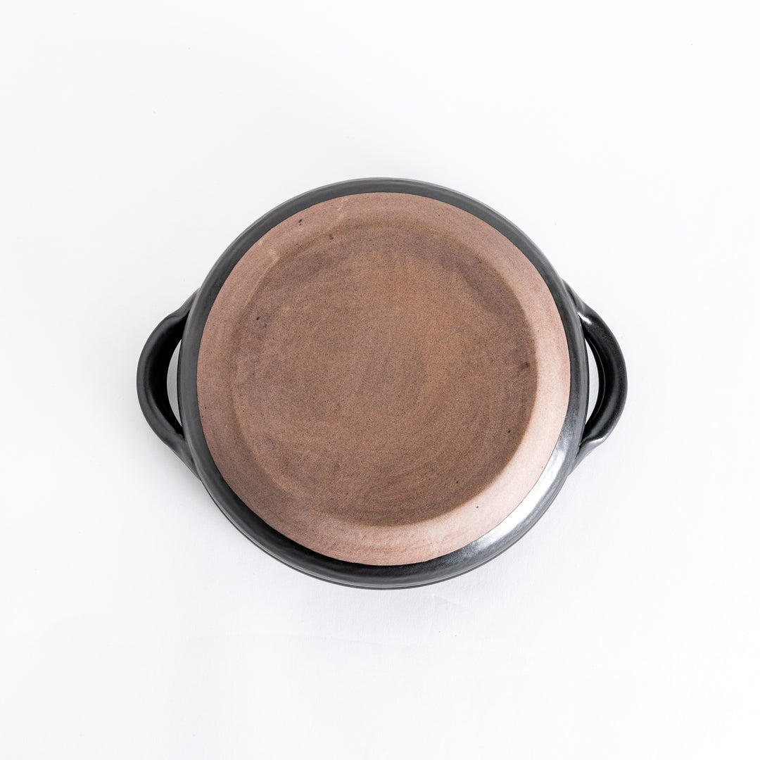 Bottom view of the donabe, showing its smooth black surface with a subtle circular base design.