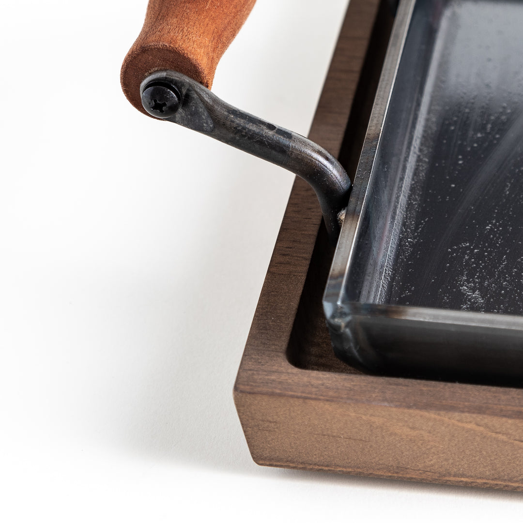 Close-up of a wooden handle attached to the cast iron griddle.