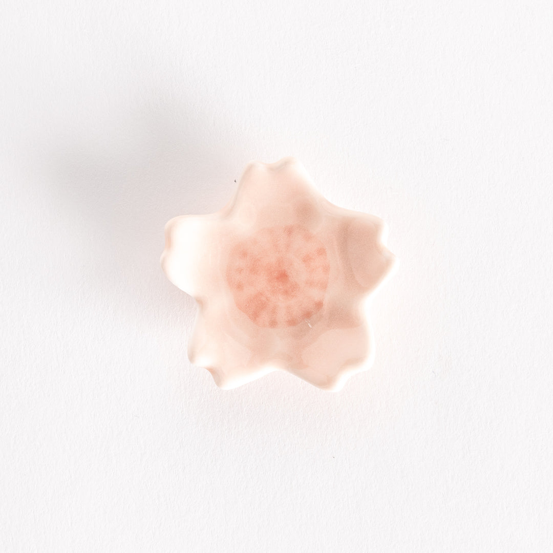 Pink cherry blossom-shaped chopstick rest with a soft, pastel finish and intricate flower center details.