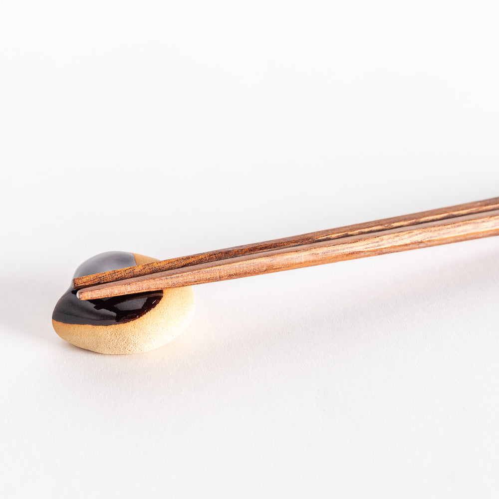 Close-up of the chestnut chopsticks rest with chopsticks placed on top, showcasing its shiny top and realistic design.