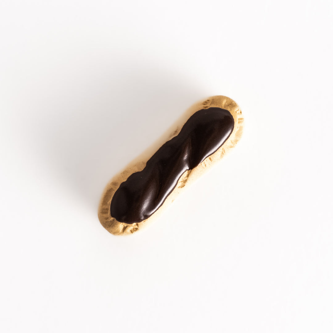 Top view of the chocolate éclair-shaped chopsticks rest, showcasing the smooth chocolate glaze and intricate details on the base.