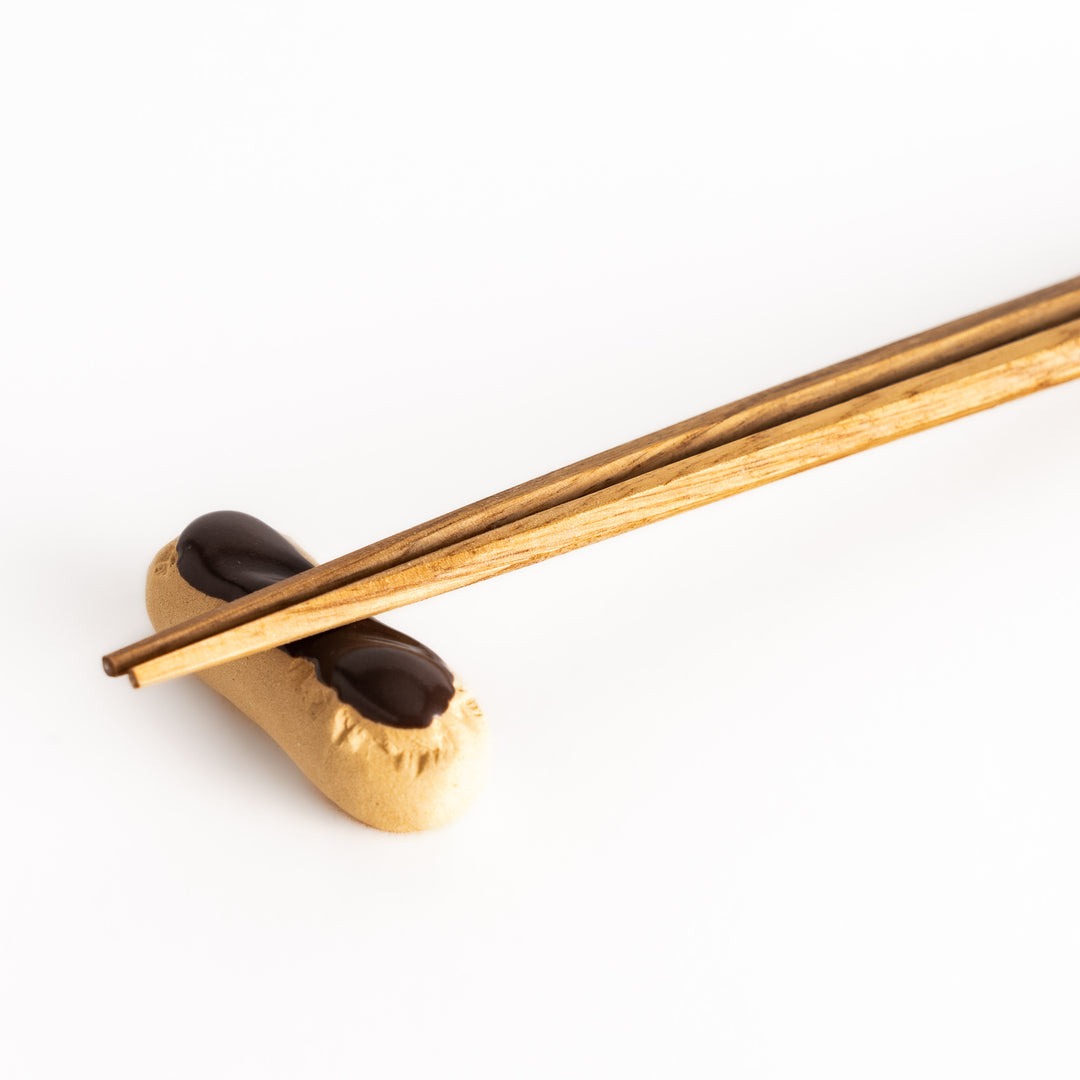 Close-up view of chopsticks placed on the chocolate éclair-shaped chopsticks rest, showcasing its lifelike texture and elegant finish.