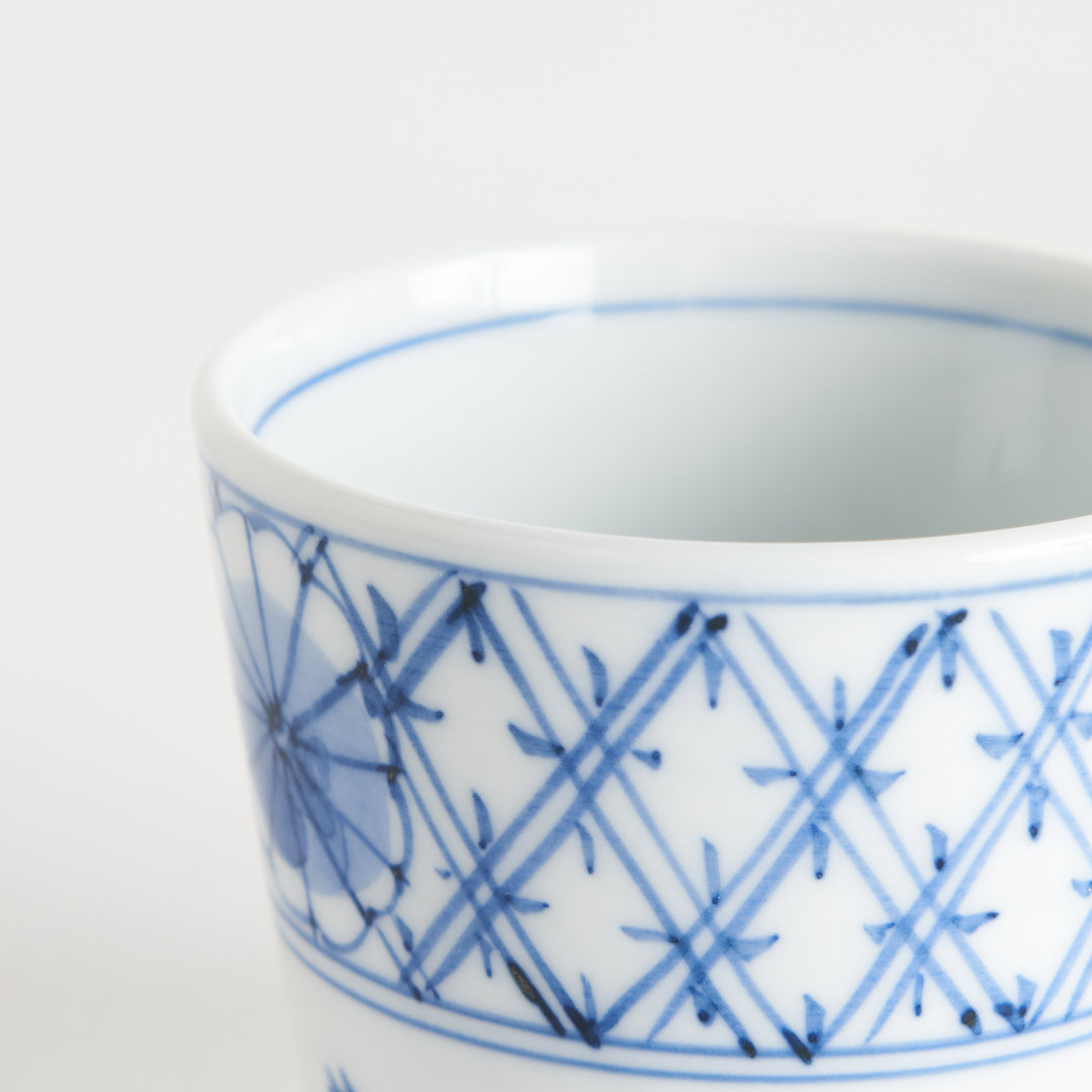 A small white condiment bowl with a delicate blue chrysanthemum and lattice pattern on the exterior.