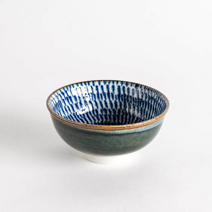 A round dessert bowl adorned with a sprial blue pattern spreading from the center.