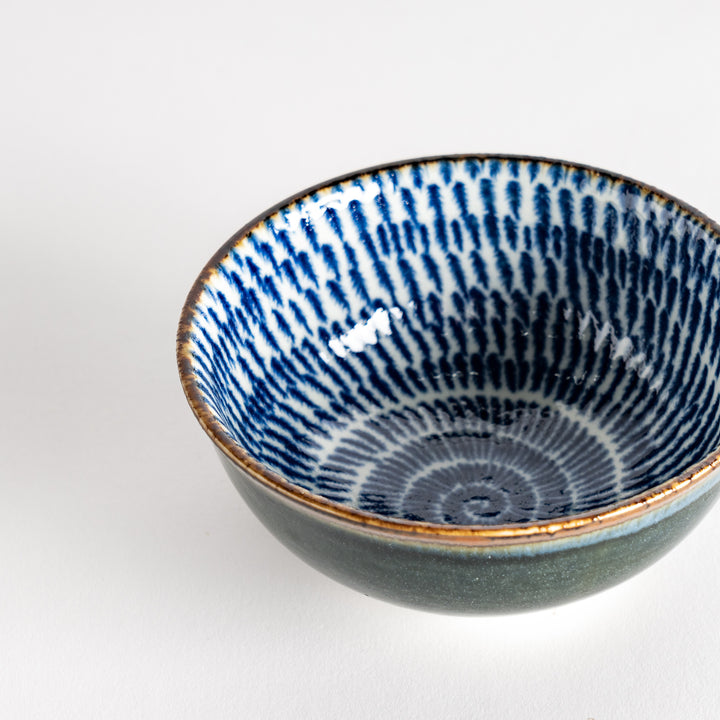 A round dessert bowl adorned with a sprial blue pattern spreading from the center.