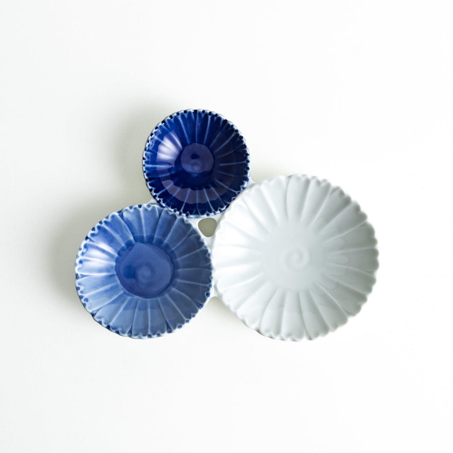 Tthree connected bowls in varying shades of blue and white, with a scalloped design.