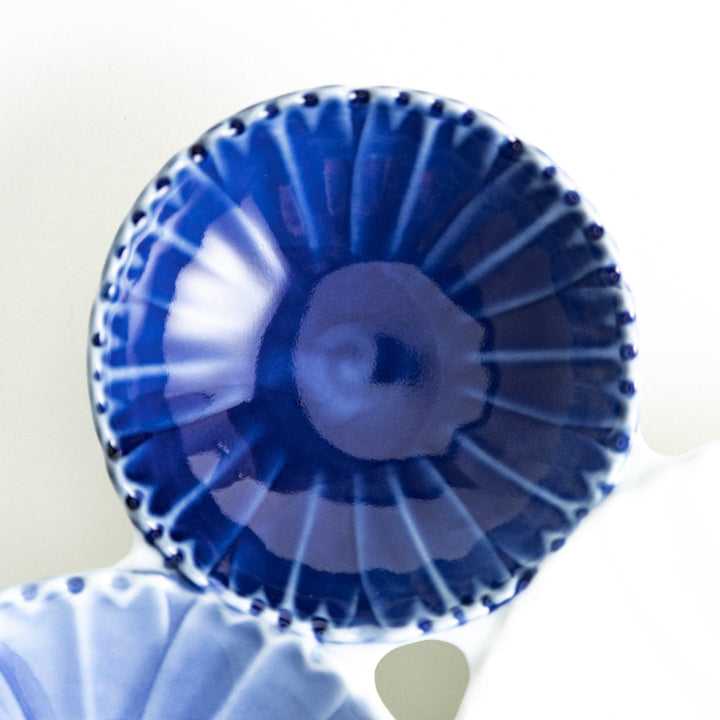 Tthree connected bowls in varying shades of blue and white, with a scalloped design.