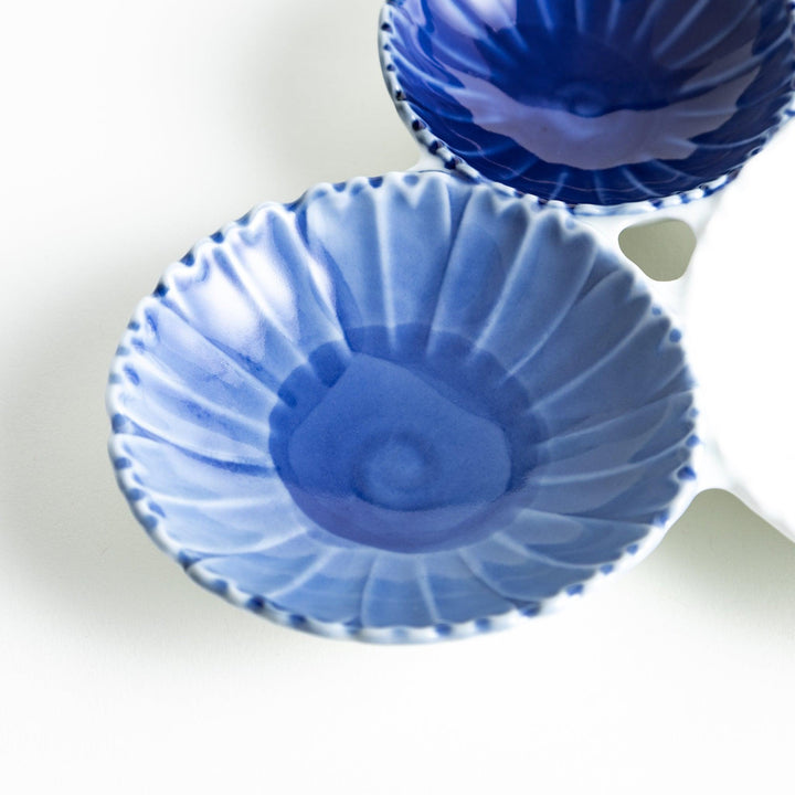 Tthree connected bowls in varying shades of blue and white, with a scalloped design.