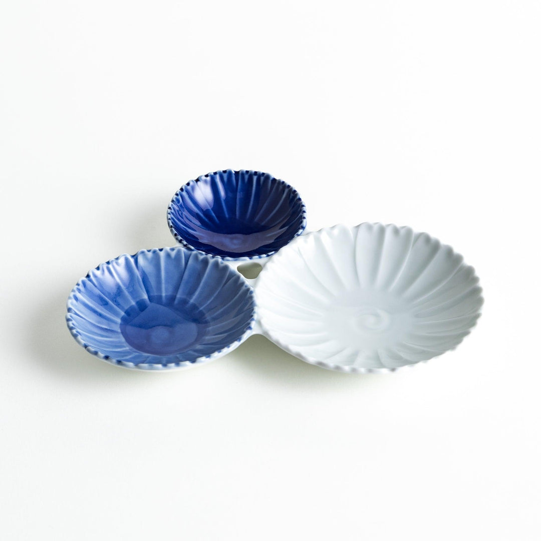 Tthree connected bowls in varying shades of blue and white, with a scalloped design.