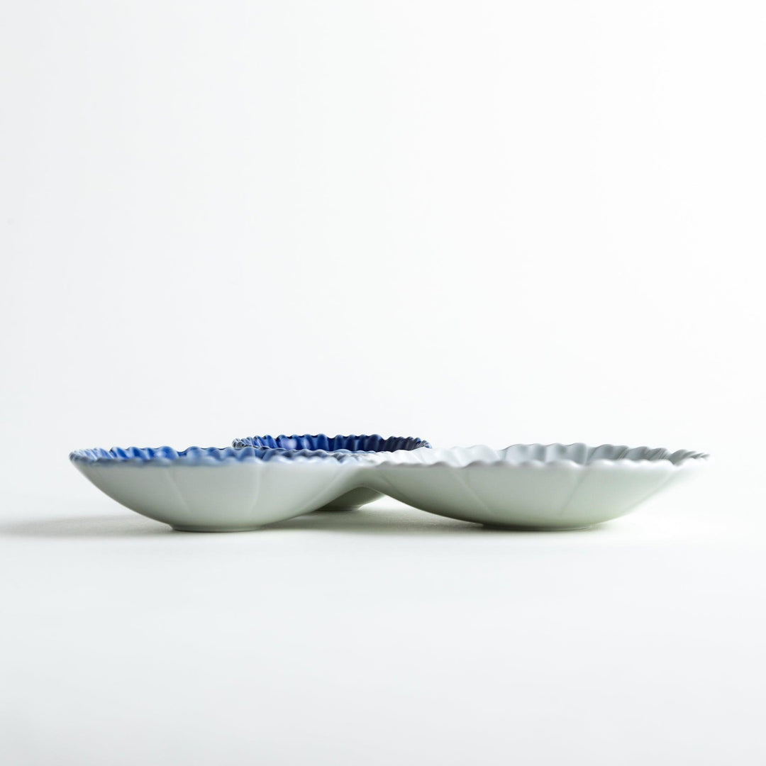 Tthree connected bowls in varying shades of blue and white, with a scalloped design.