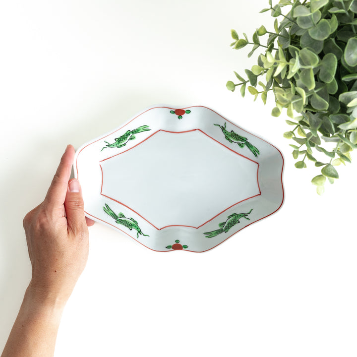 An irregularly shaped porcelain dish featuring hand-painted designs of fish and plants.