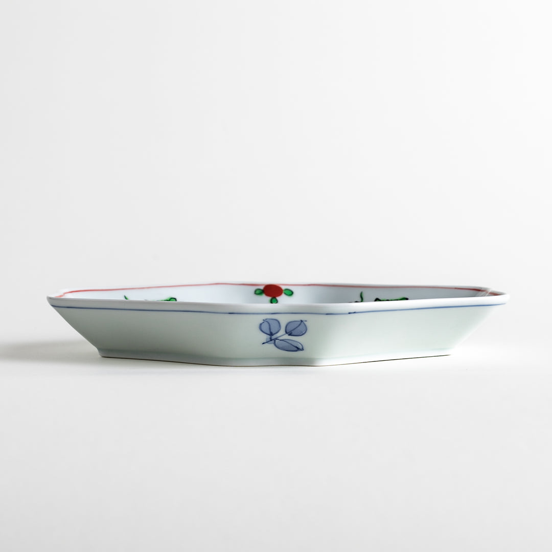 An irregularly shaped porcelain dish featuring hand-painted designs of fish and plants.