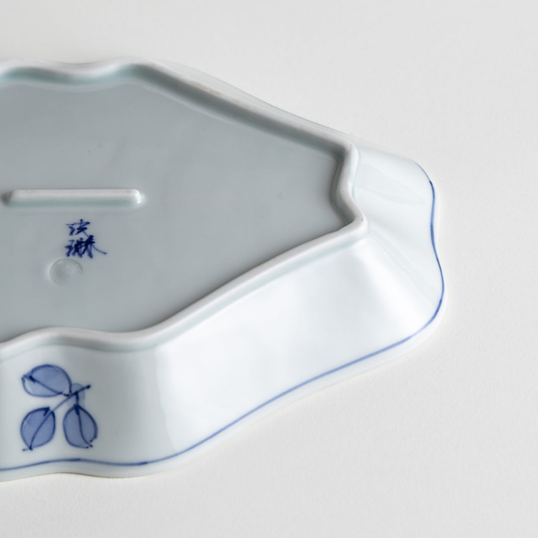 An irregularly shaped porcelain dish featuring hand-painted designs of fish and plants.