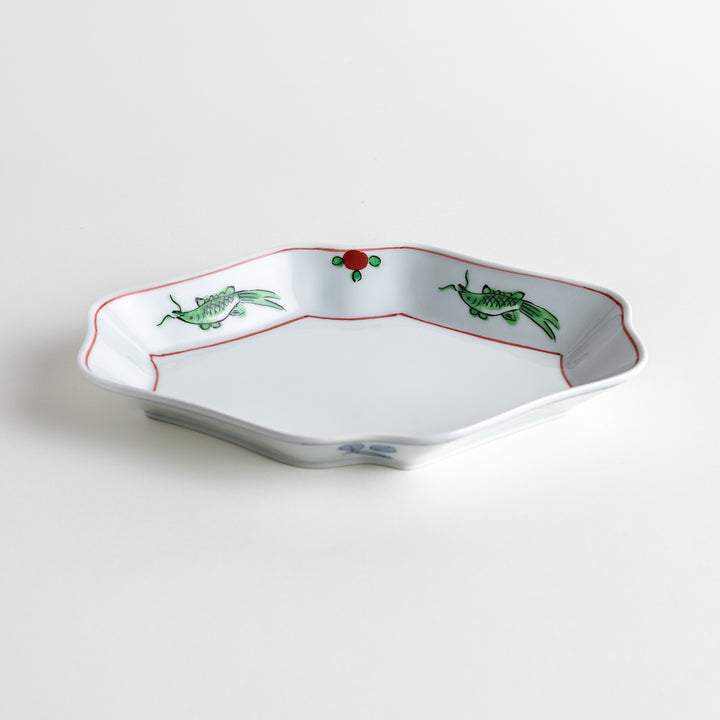 An irregularly shaped porcelain dish featuring hand-painted designs of fish and plants.