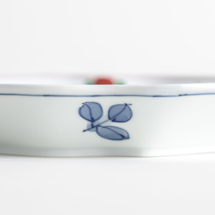 An irregularly shaped porcelain dish featuring hand-painted designs of fish and plants.