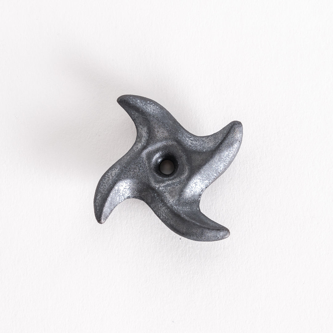 Close-up of a black ninja star-shaped chopstick rest with a pointed design and a small hole at the center, capturing its geometric, angular appearance.