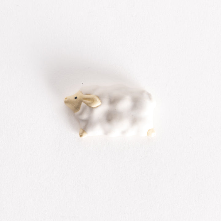 Ceramic sheep-shaped chopsticks rest featuring a fluffy white body and beige face, mimicking a cloud-like design.