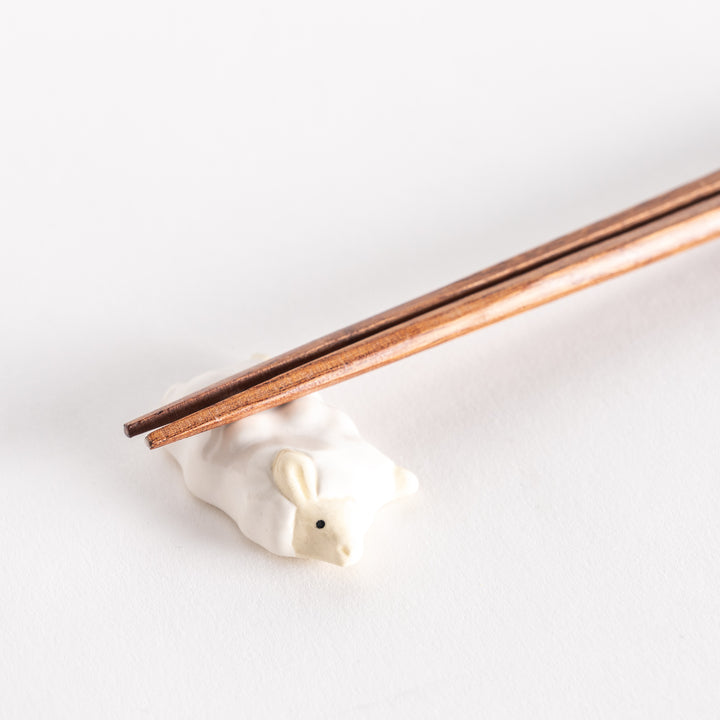 Close-up view of the sheep-shaped chopsticks rest with chopsticks gently placed on its back.