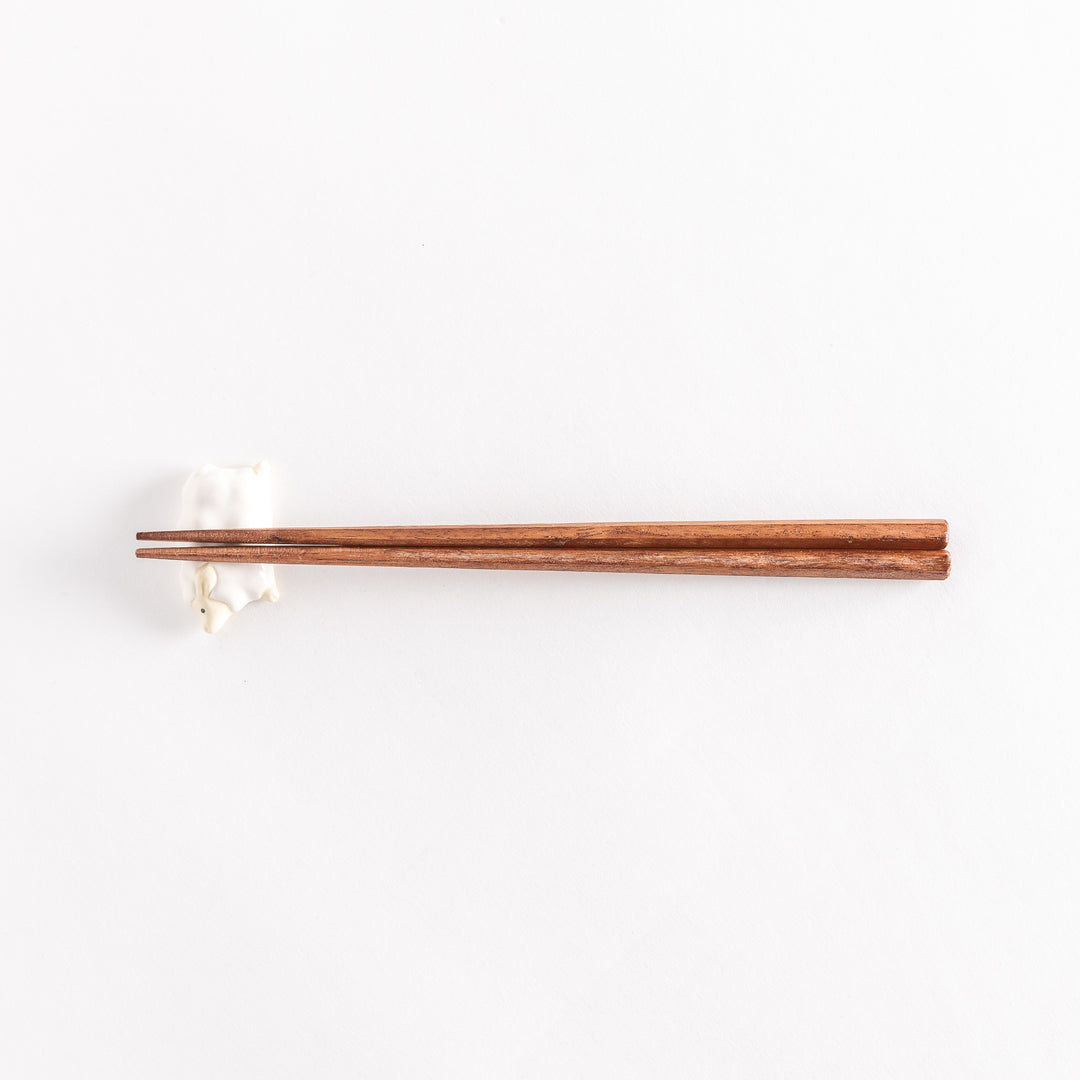 Full view of the sheep chopsticks rest with chopsticks resting across its soft, rounded body.