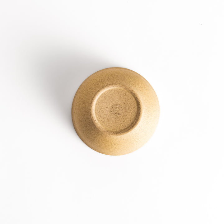 Bottom view of a beige ceramic teacup, showcasing its base and craftsmanship details.