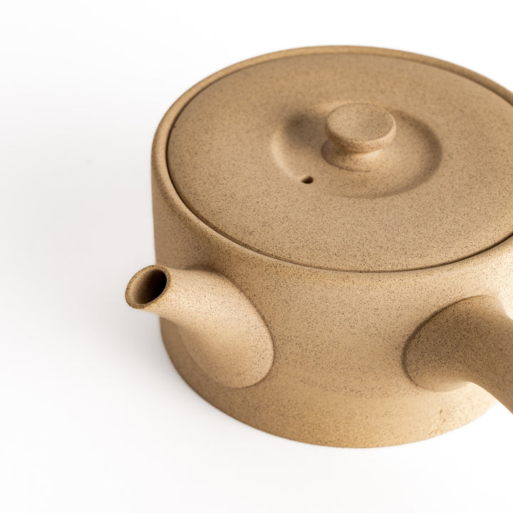 Close-up of the beige teapot’s spout and textured ceramic surface, emphasizing its craftsmanship and detail.