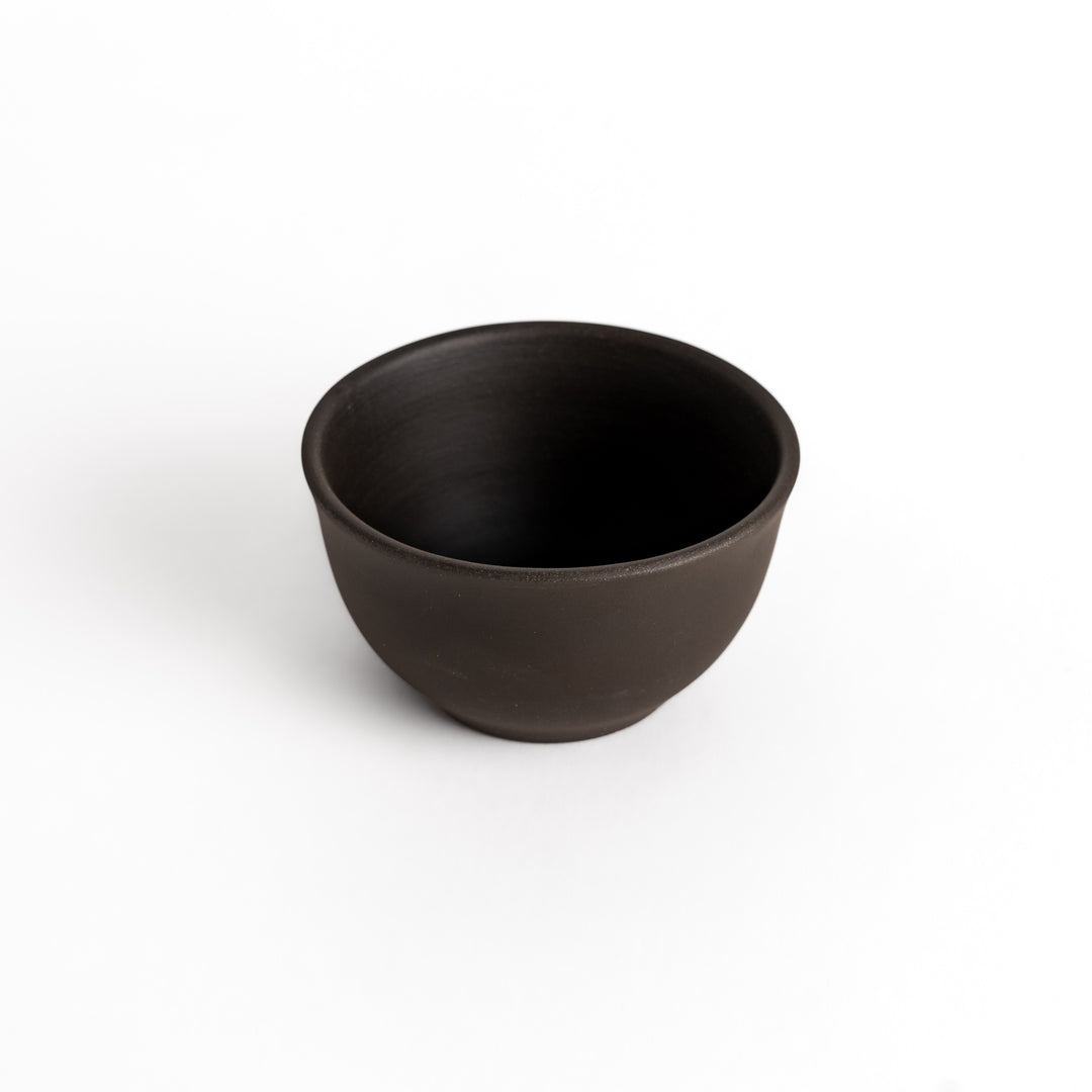 Slightly angled shot of a black ceramic teacup, emphasizing its balanced form and minimalist design.