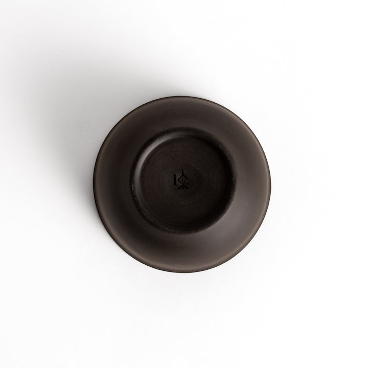 Bottom view of a black ceramic teacup, showcasing its base and craftsmanship details.