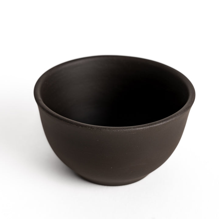 Close-up of the black teacup, focusing on its smooth matte surface and gently rounded edges.