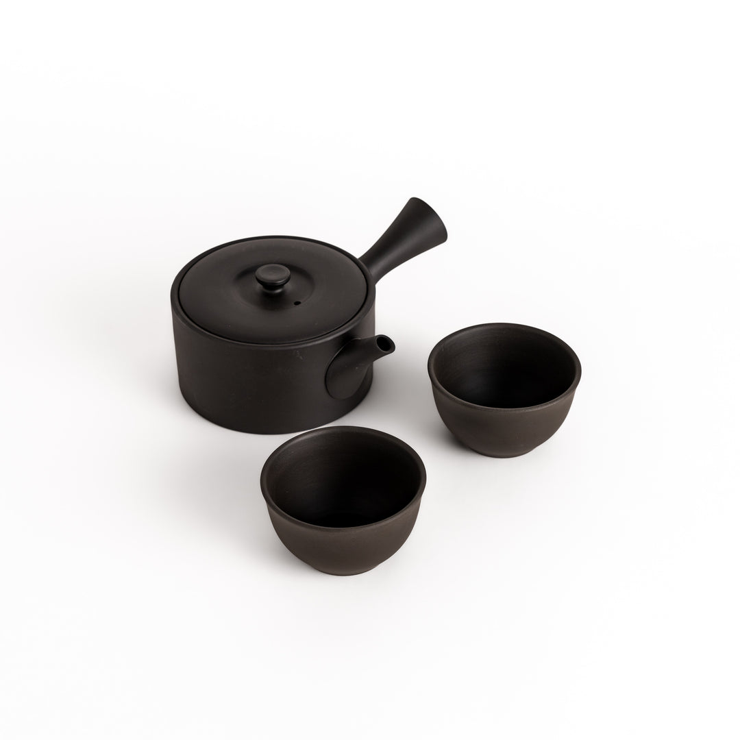 Black teacups paired with a matching teapot, creating a harmonious set for a refined tea-drinking experience.