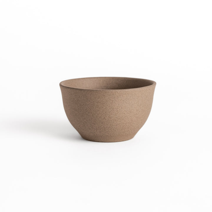 Gray ceramic teacup photographed from the side, highlighting its elegant curved silhouette and textured surface.