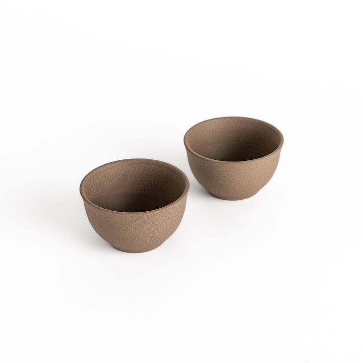 Two gray ceramic teacups with a textured surface, displayed side by side, part of a beautifully crafted two-piece set.