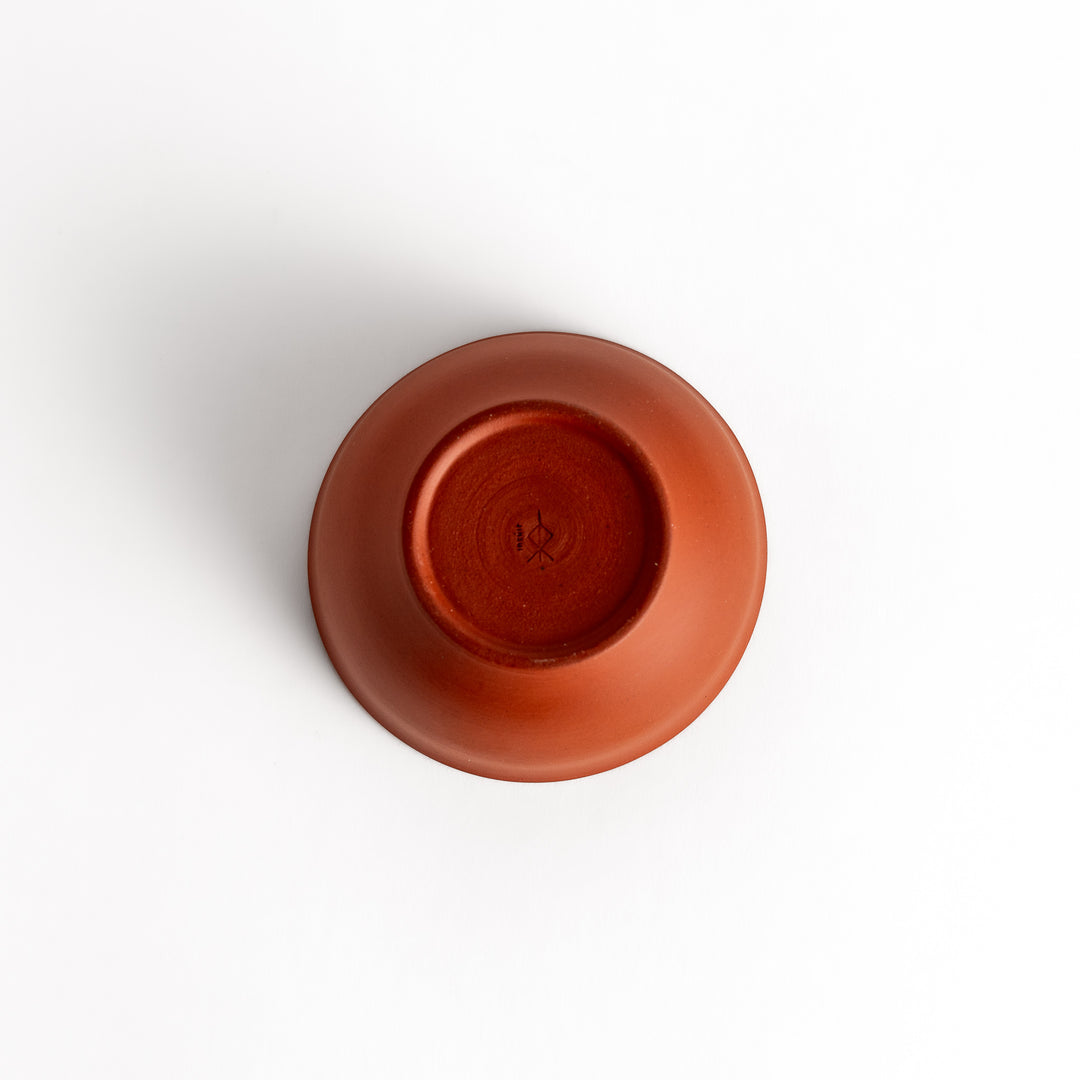 Bottom view of a single red teacup, showcasing its sturdy base and subtle craftsmanship.