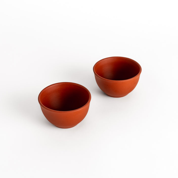 Two red teacups side by side, part of a matching set designed for a harmonious tea experience.