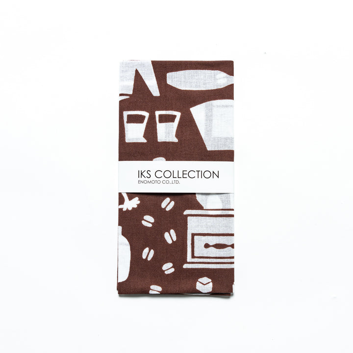 A neatly folded brown tenugui with a branded paper sleeve, showcasing barista-themed patterns.