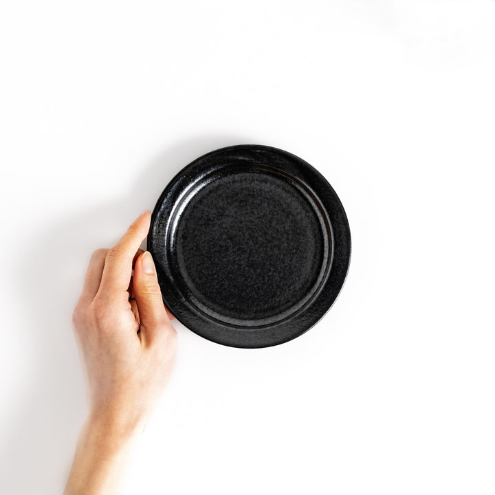 Hand-held black ceramic dessert plate showcasing its sleek glossy surface and compact size, ideal for everyday dining or special occasions.