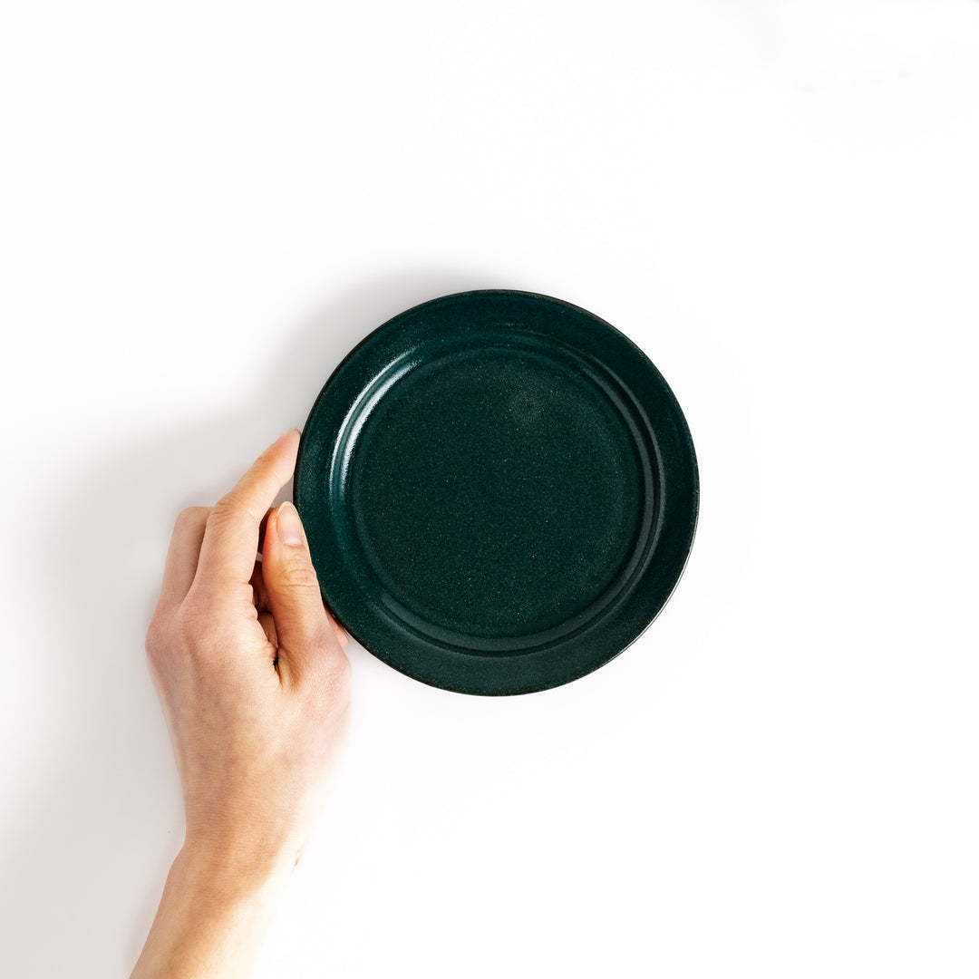 Hand-held green ceramic dessert plate showcasing its sleek glossy surface and compact size, ideal for everyday dining or special occasions.