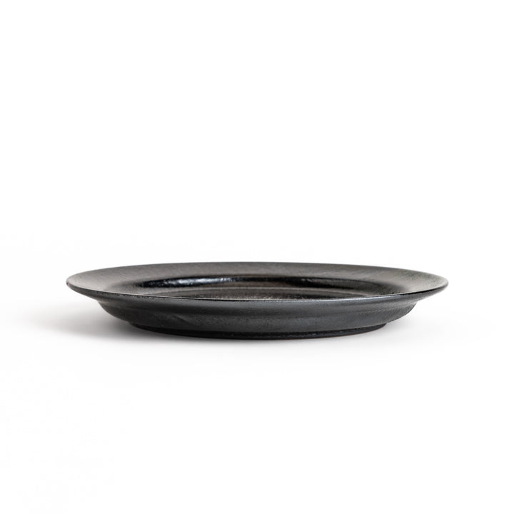 Black ceramic dinner plate with a glossy finish, showing its smooth texture. Minimalist design adds elegance to any table setting.