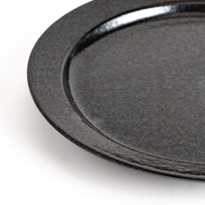 Black ceramic dinner plate with a glossy finish, showing its smooth texture. Minimalist design adds elegance to any table setting.