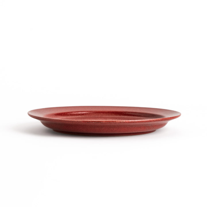 Red ceramic dinner plate with a glossy finish, providing a bold and vibrant accent to any dining arrangement.